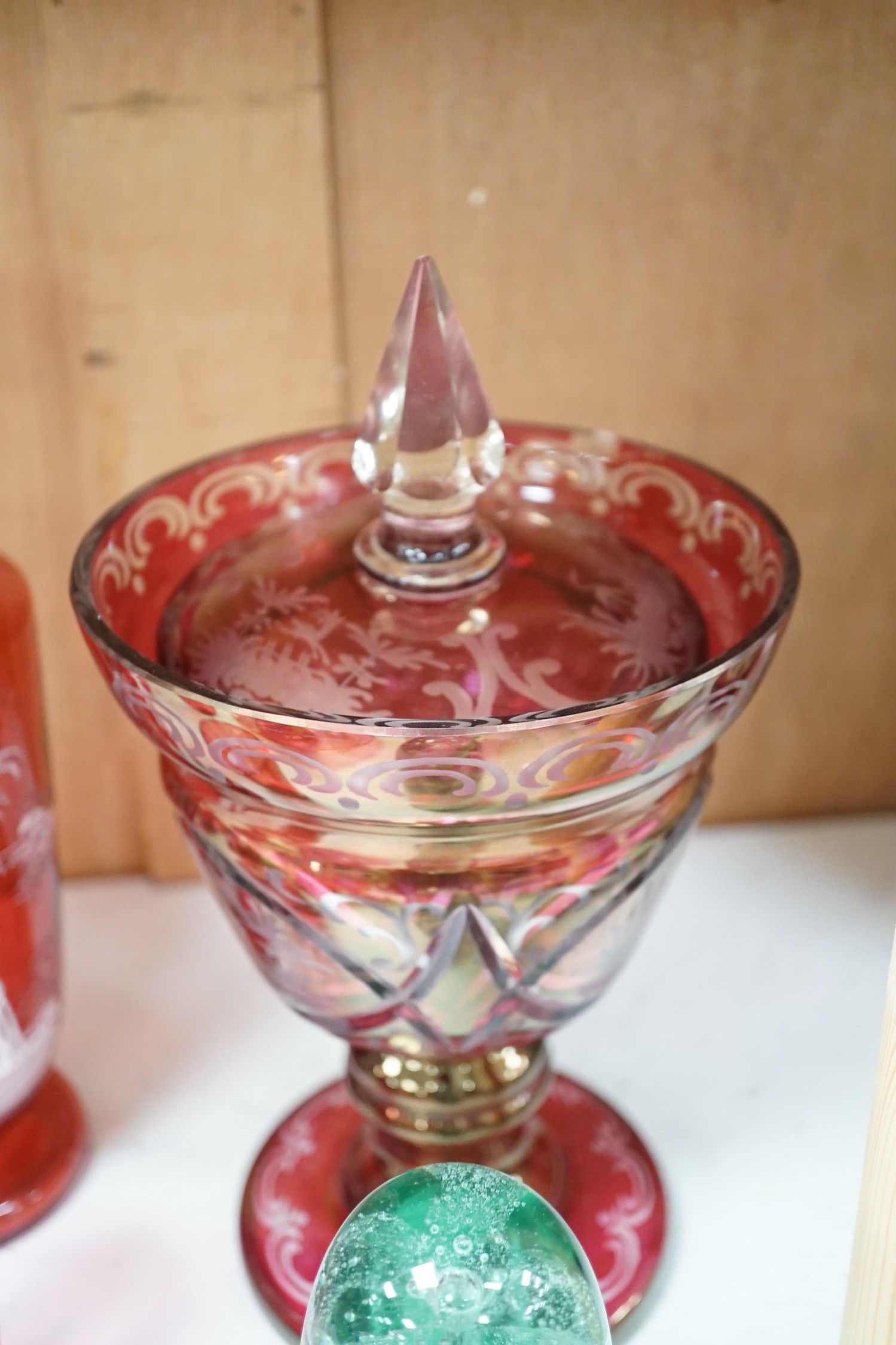 A collection of cranberry glass, a dump paperweight, another and a sweetmeat jar, tallest 28.5 cm